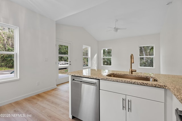 kitchen with stainless steel dishwasher, white cabinetry, vaulted ceiling, a sink, and light wood-type flooring