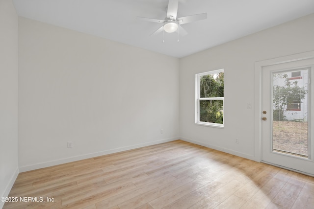 spare room with a ceiling fan, light wood-type flooring, and baseboards