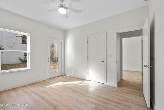 interior space with ceiling fan, access to outside, light wood-style flooring, and baseboards