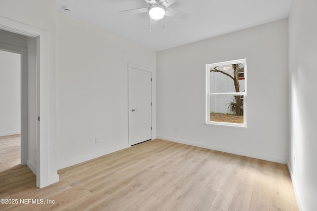 unfurnished room with a ceiling fan, light wood-type flooring, and baseboards