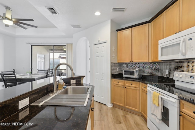 kitchen with white appliances, visible vents, light wood-style flooring, a sink, and backsplash