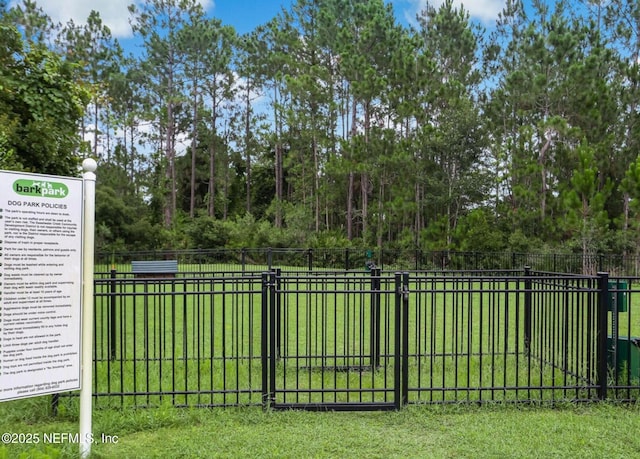 view of gate with fence and a lawn