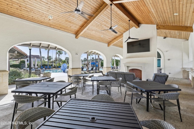 view of patio / terrace with outdoor dining space, an outdoor pool, ceiling fan, and an outdoor fireplace