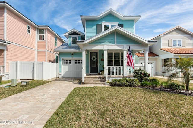 view of front of home featuring decorative driveway, covered porch, a front yard, fence, and a garage