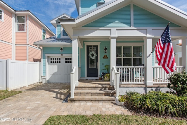 view of front of house with decorative driveway, a porch, a standing seam roof, metal roof, and fence