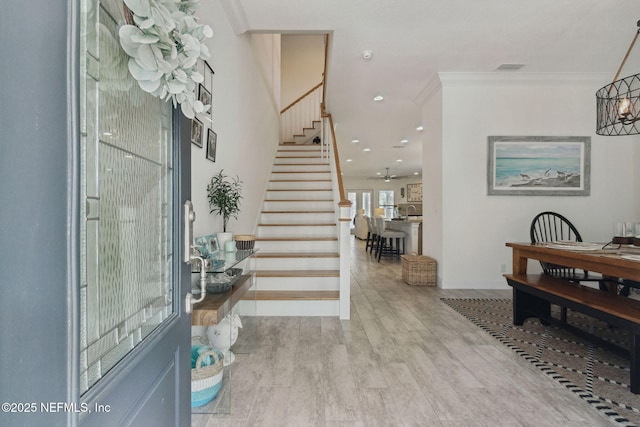 entryway featuring visible vents, ornamental molding, wood finished floors, baseboards, and stairs