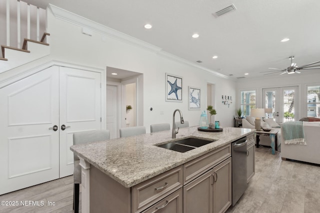 kitchen with a sink, light wood-style floors, french doors, ornamental molding, and dishwasher