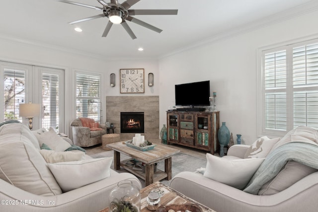 living room featuring ceiling fan, a fireplace, ornamental molding, and recessed lighting