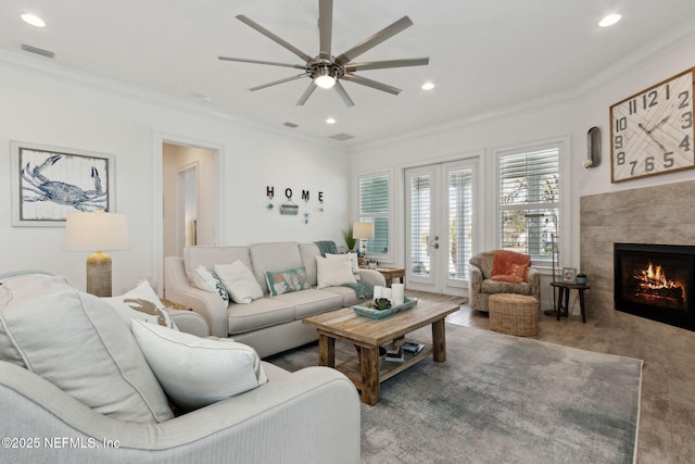 living room featuring recessed lighting, ornamental molding, a tiled fireplace, and french doors