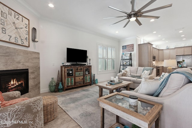 living room featuring light wood-type flooring, recessed lighting, a fireplace, and crown molding