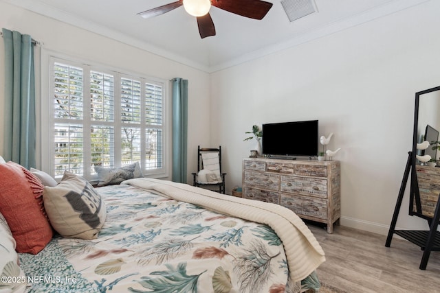 bedroom with light wood-type flooring, visible vents, ornamental molding, and baseboards