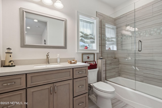 bathroom with toilet, shower / bath combination with glass door, and vanity