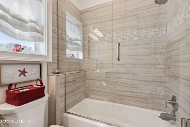 bathroom with combined bath / shower with glass door and toilet