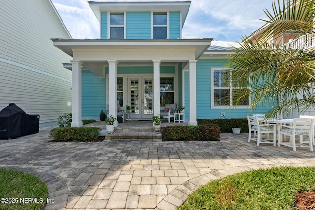 property entrance with covered porch, metal roof, and french doors