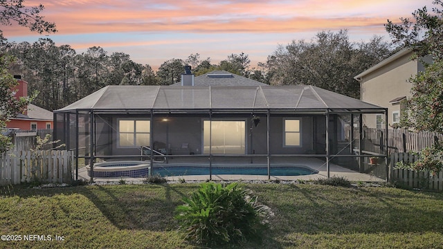 rear view of property featuring a lanai, a fenced backyard, and a lawn