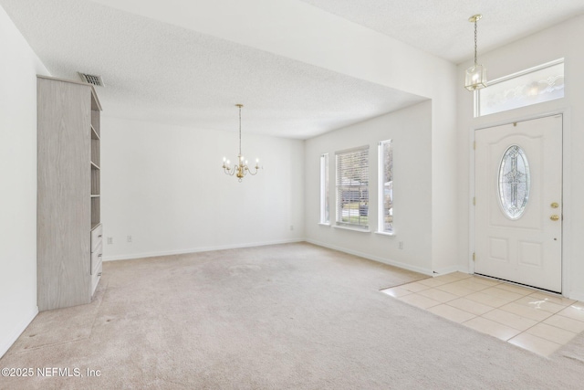 tiled entryway with baseboards, visible vents, a textured ceiling, carpet flooring, and a notable chandelier