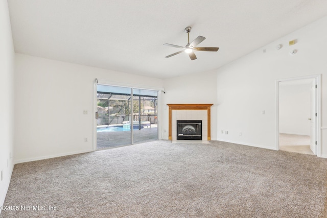 unfurnished living room featuring lofted ceiling, ceiling fan, a fireplace, baseboards, and carpet