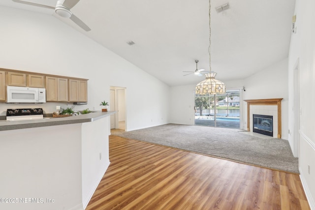 kitchen featuring white microwave, a tile fireplace, visible vents, open floor plan, and range