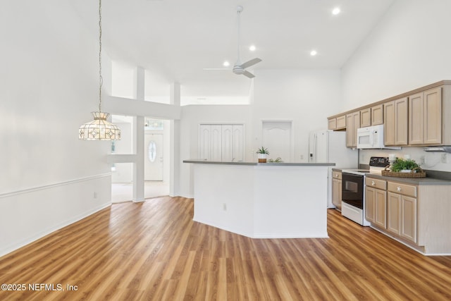 kitchen featuring white appliances, a ceiling fan, a high ceiling, and light wood-style floors