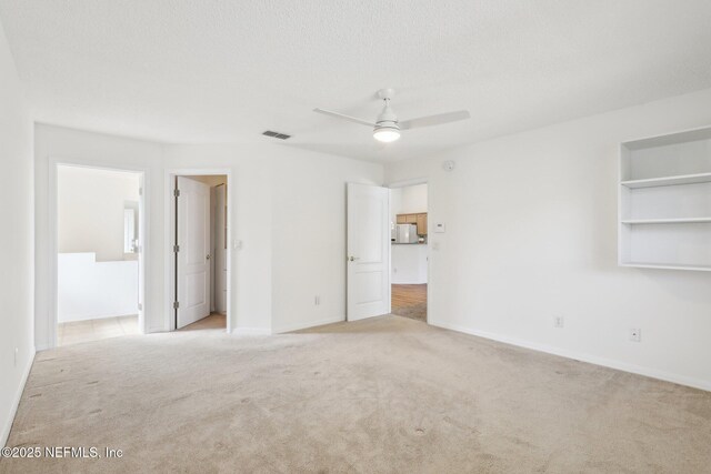 unfurnished bedroom featuring baseboards, visible vents, light colored carpet, a spacious closet, and a textured ceiling