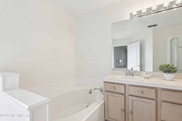 bathroom with visible vents, a garden tub, and vanity