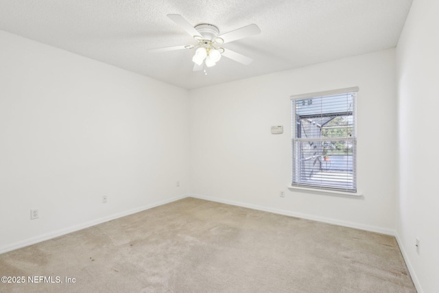 spare room featuring light carpet, ceiling fan, a textured ceiling, and baseboards