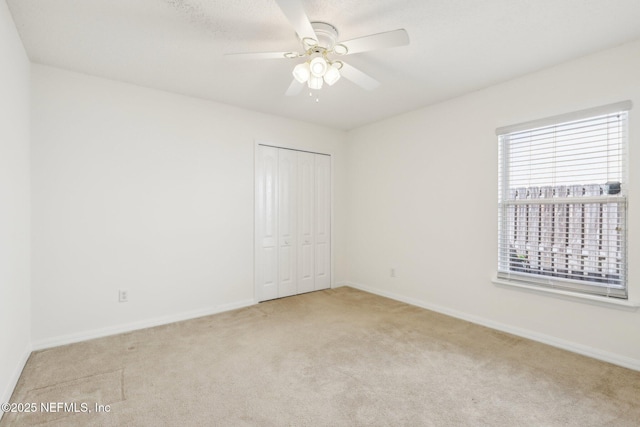 unfurnished bedroom with a closet, carpet flooring, ceiling fan, and baseboards