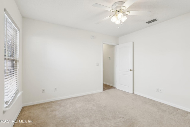 spare room with ceiling fan, carpet floors, visible vents, and baseboards