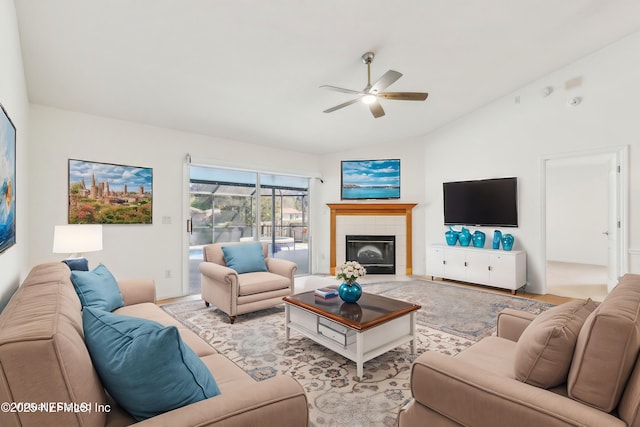 living room featuring a ceiling fan, lofted ceiling, and a tiled fireplace