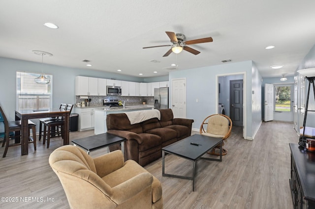 living area featuring light wood-type flooring, baseboards, and recessed lighting