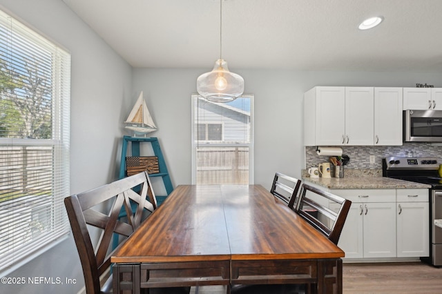 dining area featuring a healthy amount of sunlight, light wood-type flooring, and recessed lighting