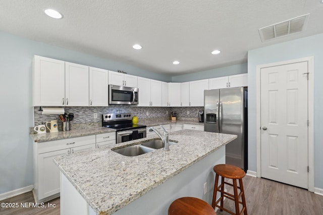 kitchen with stainless steel appliances, visible vents, a sink, and white cabinetry