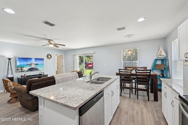 kitchen with visible vents, white cabinets, appliances with stainless steel finishes, light wood-style floors, and a sink