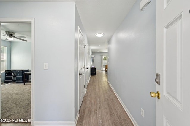 corridor with baseboards and wood finished floors