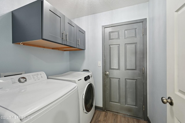 laundry room with dark wood-type flooring, washer and dryer, cabinet space, and a textured ceiling