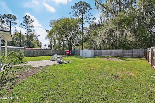 view of yard with a fenced backyard, a storage unit, an outbuilding, and a patio