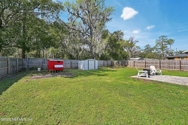 view of yard featuring an outbuilding, a storage unit, a patio area, and a fenced backyard