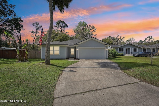 ranch-style home with a front yard, concrete driveway, fence, and an attached garage