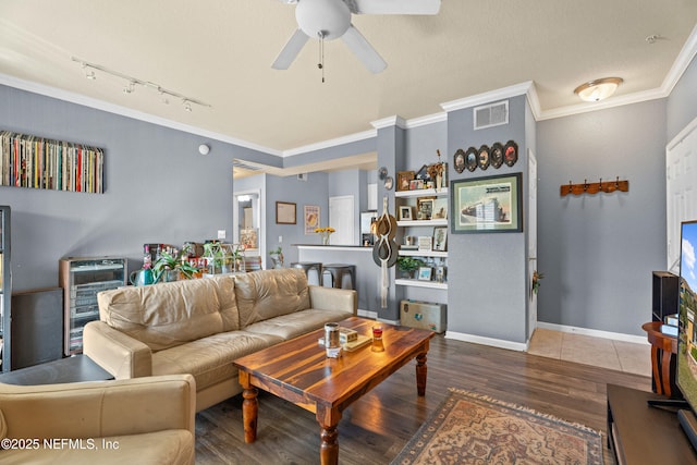 living area with ceiling fan, wood finished floors, visible vents, baseboards, and crown molding