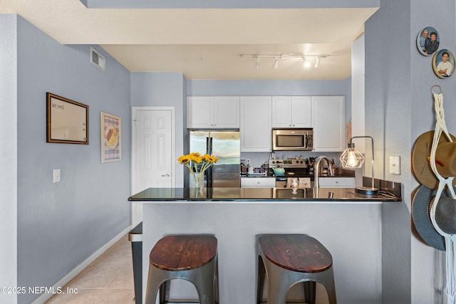 kitchen featuring stainless steel appliances, a peninsula, visible vents, white cabinetry, and dark countertops