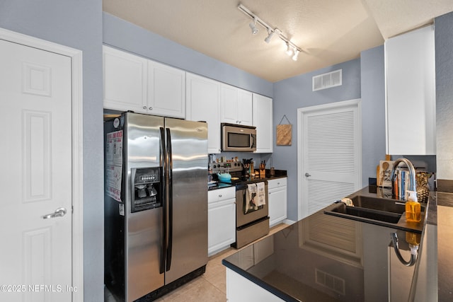 kitchen featuring dark countertops, visible vents, appliances with stainless steel finishes, and a sink