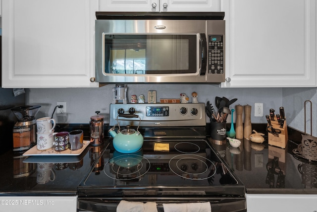 kitchen with dark countertops, appliances with stainless steel finishes, and white cabinets