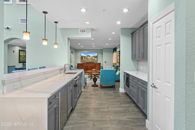 kitchen with light stone counters, a sink, visible vents, and gray cabinetry