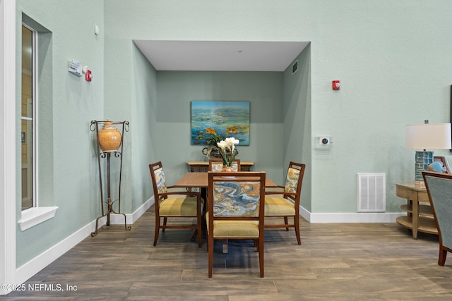 dining area with baseboards, visible vents, and wood finished floors