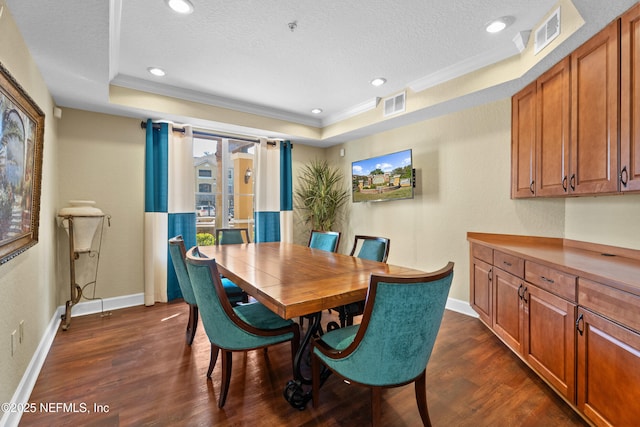 dining space featuring a textured ceiling, a tray ceiling, dark wood-type flooring, and visible vents