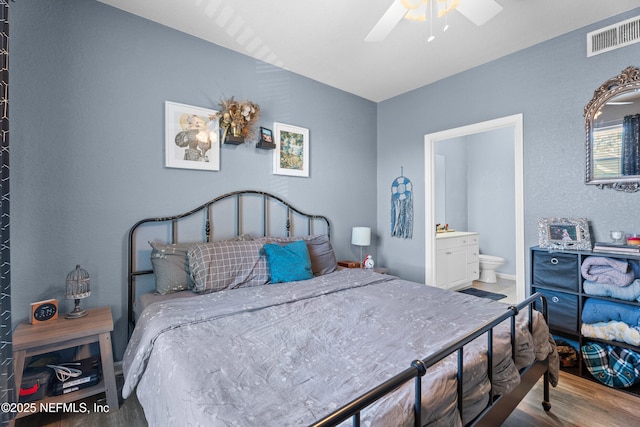 bedroom featuring a ceiling fan, wood finished floors, visible vents, and connected bathroom