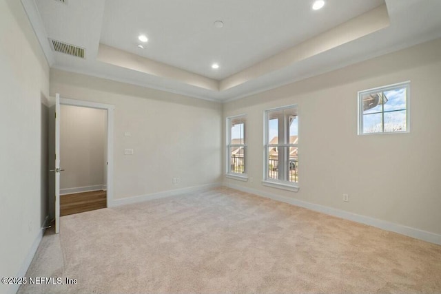 empty room featuring carpet, a raised ceiling, visible vents, and baseboards