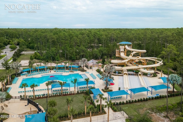 view of swimming pool featuring a wooded view