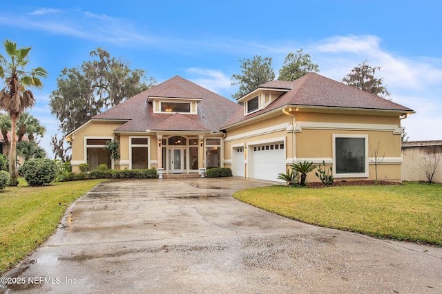 view of front facade featuring driveway, a shingled roof, an attached garage, a front lawn, and stucco siding