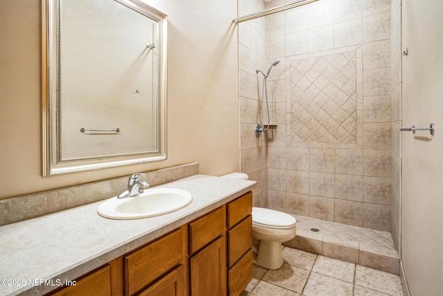 full bathroom featuring tile patterned flooring, tiled shower, vanity, and toilet